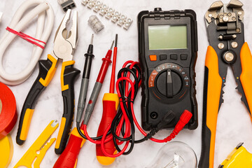 Electrician tools on background.Multimeter,construction tape,electrical tape, screwdrivers,pliers,an automatic insulation stripper, socket and LED lamp.Flatley.electrician concept.