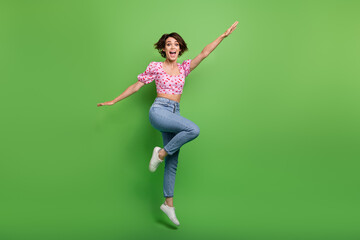 Fototapeta na wymiar Full size photo of pretty young girl jumping run activity dressed stylish pink cherry print outfit isolated on green color background