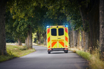 Yellow ambulance car of emergency medical service on country road. Themes rescue, urgency and health care. .