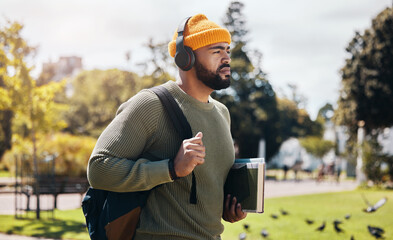 Man on campus, walking with books and headphones on morning commute for education with backpack....