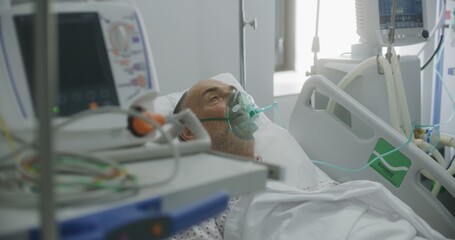 Sick elderly man in oxygen mask in bed in hospital ward. Old patient with pneumonia during lung...