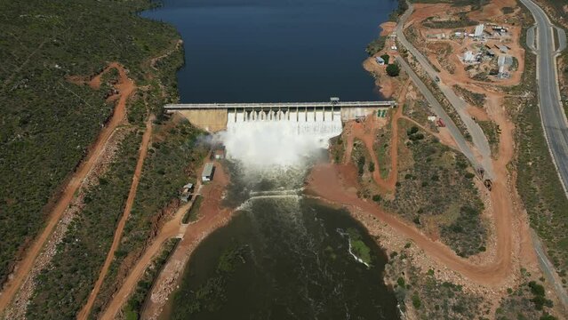 Clanwilliam Dam wall in Olifants River valley, sluice gates overflowing with construction base nearby