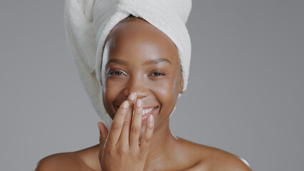 Portrait, beauty and cream with a happy black woman in studio on a gray background for natural...