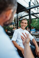 Handsome and happy father and his teenager son sitting in a restaurant and talking.