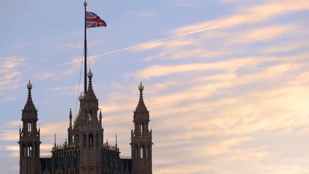 Closeup view of the top of the Westminster Palace parliament building with a british flag waiving in the sunset, London, England