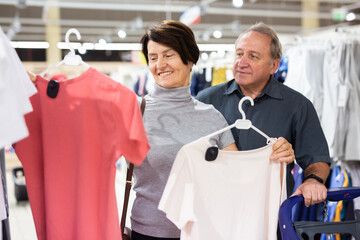 Elderly man and elderly woman choose t-shirt