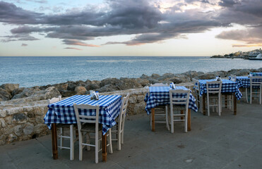 Fototapeta na wymiar Empty beach tavern restaurant at Paleochora town, Crete island Greece. Rocky landscape, sea, sky.