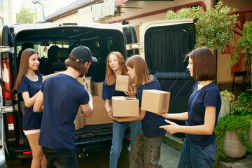 Young people, volunteers in uniform loading boxes into van. Gathering food, clothes, meds for...