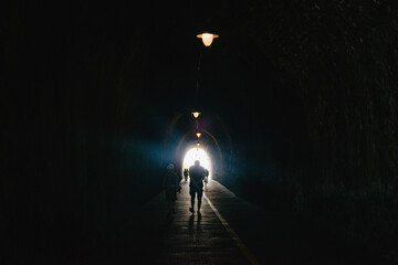 A dark tunnel. Silhouettes of people