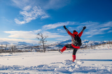 Sporty person in red sport jacket enjoys snow and breathtaking Norwegian landscape. Sunny winter...