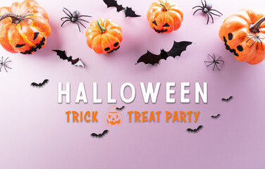 Halloween decorations made from pumpkin, paper bats, black spider on pastel background