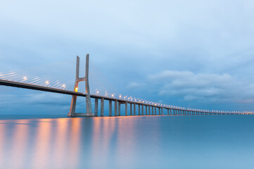 Vasco da Gama suspension bridge with lights at sunset in Lisbon, Portugal.