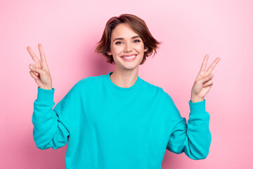 Photo of cute girl showing popular youth v sign gesture good mood wear oversize teal shirt isolated...