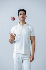 Portrait of Cricketer holding cricket boll in hand and looking towards the camera in aggression ,...