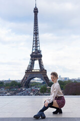 Beautiful blonde in Paris with the Eiffel Tower.  The girl is on a trip to France. Fashion woman  in romantic city. Beautiful elegant girl in Paris on the background of the Eiffel Tower.