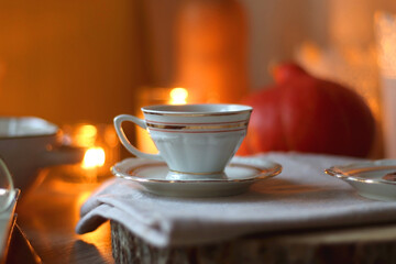 Vintage books, reading glasses, cup of tea or coffee, bowl of cookies, pumpkin and lit candles on the table. Hygge at home, fall atmosphere. Selective focus.