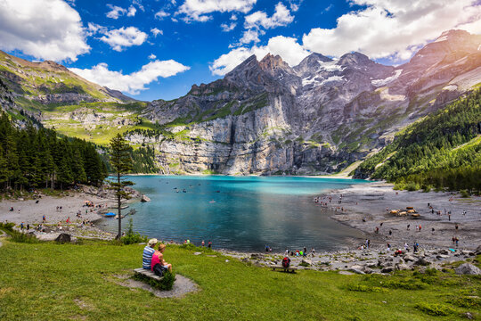 Famous Oeschinensee with Bluemlisalp mountain on a sunny summer day. Panorama of the azure lake Oeschinensee. Swiss alps, Kandersteg. Amazing tourquise Oeschinnensee with waterfalls, Switzerland.