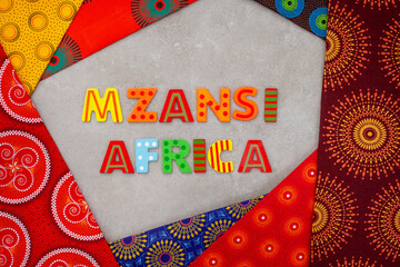 Mzansi, a slang word for South Africa, in colorful letters with iconic South African Shwe Shwe fabric - obrazy, fototapety, plakaty