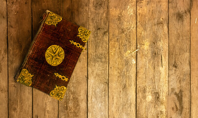 An old book with decorative cover lying on an old table from planks