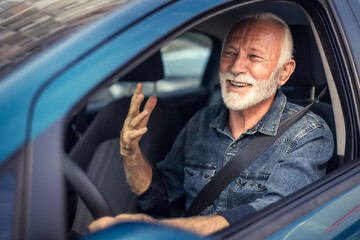 Cheerful senior man having fun in his new car.