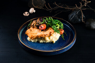 Breaded chicken fillet with mashed potatoes, mushrooms, arugula, lettuce and cherry tomatoes.