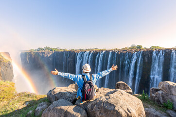 Man sitting on the top of a rock enjoying the Victoria Falls - Zimbabwe - obrazy, fototapety, plakaty