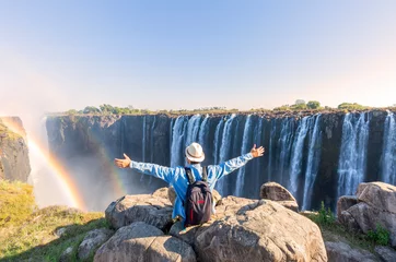 Foto op Aluminium Man sitting on the top of a rock enjoying the Victoria Falls - Zimbabwe © minoandriani