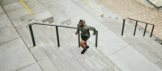 Fitness, city and black man running on stairs outdoor, exercise and training healthy body in urban town top view. Sports, cardio and African athlete on steps for workout, energy and jog for wellness