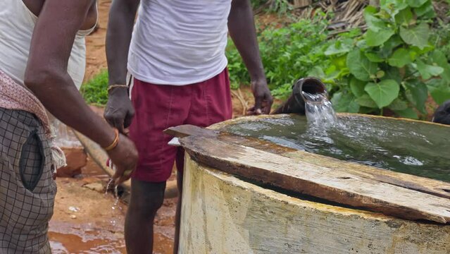 A tired farmer washes his hands and legs after a hard day in the field