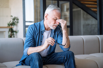 Man holding glasses and touching nose bridge, feeling eye strain