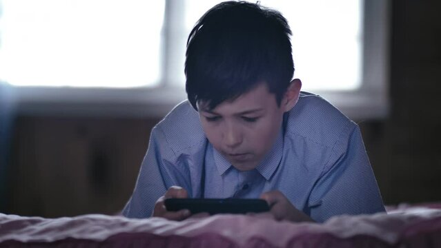 Bedtime Gaming: Boy Relaxing on Bed, Playing on Phone