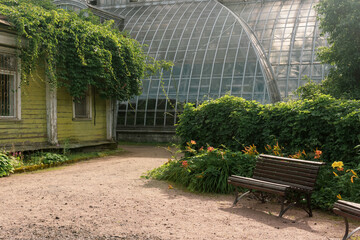 corner of an old botanical garden with a huge vintage greenhouse in the background