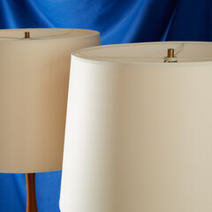 Pair of vintage stylish white lampshades. Interior product photograph with a blue background.