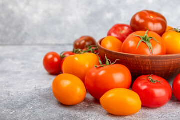 Tomatoes on marble texture background. Cherry tomatoes, yellow, pink, brown and black tomatoes in a bowl. Organic vegetables, harvesting.Vegan. Fresh ripe tomatoes. copy space.