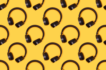 Repetitive pattern made of black wireless headphones on a yellow background.