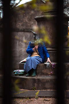 Personaje de Edinburgo. Bruja de cuento sentada mientras lee libros en el cementerio. 