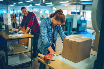 Young Caucasian woman sealing a box while working in warehouse