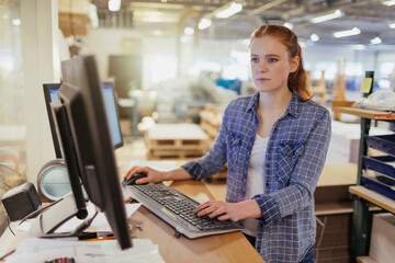 Young woman working on a computer in a printing press office