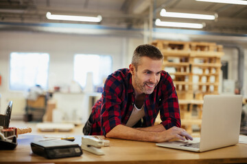 Middle aged Caucasian man working on a laptop in a printing press office