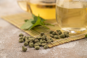 Green oolong tea with herbs in glass on brown concrete. Side view, selective focus.