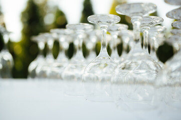 A lot of empty wine glasses. Row of clean glass transparent glasses are on a table on banquet in a...