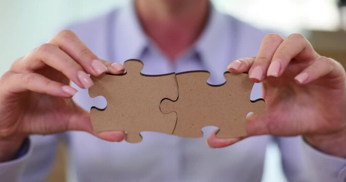 Executive manager in blouse putting together wooden puzzle pieces. Lady office clerk collects puzzle pieces together in corporate firm slow motion