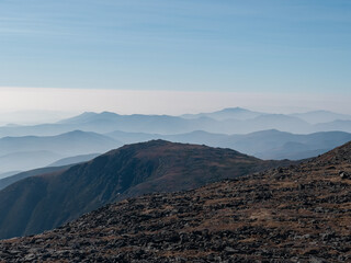 Obraz premium A vast and layered landscape of mountains. The blue tone mountains under the clear sky continue for miles into a vanishing point of mountainscapes. White Mountains of New Hampshire.