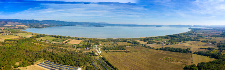 Fototapeta na wymiar Panoramic aerial view of Lake Trasimeno. Lake Thrasimene is located in the province of Perugia, in the Umbria region of Italy on the border with Tuscany. Around there are cultivated fields.