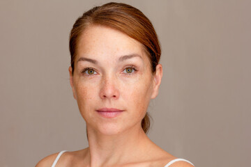 Portrait of caucasian middle aged woman of 40s looking at camera on gray background 