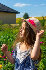 A pretty caucasian girl in a straw hat relaxing among the greenery on a sunny summer day. Happy childhood.