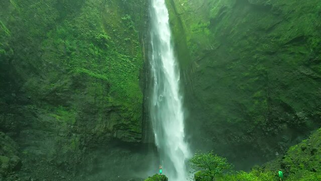 Beautiful rain forest foggy waterfall. Kabut Pelangi air terjun in Lumajang, East Java Timur. Aerial dramatic drone view.