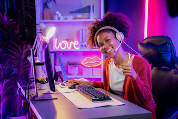 African American girl gaming streamer team winner playing online fighting with Esport wearing headphones in neon lighting room. Talking other players planing strategies to win competitors. Tastemaker. © InfiniteFlow