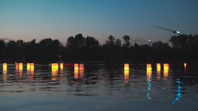 Young woman on a stand up paddle board sup on a lake during floating lantern lights festival at night 