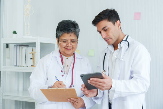 Female Doctor Male Assistant, Two People Were Standing Talking About Condition Patient Waiting Be Treated, Viewing Patient Symptom-based Treatment Plan On Laptop, There Was No Worry On Doctor Face.